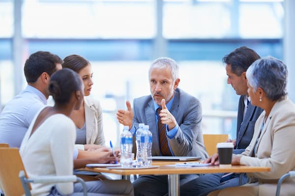 A senior sales team manager conducts a strategy session at a table in a modern building