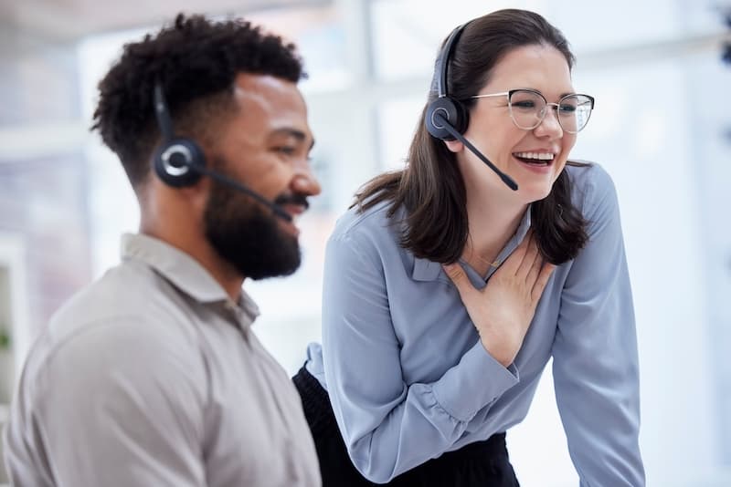 Two customer support professionals wearing headsets in a shared office workspace
