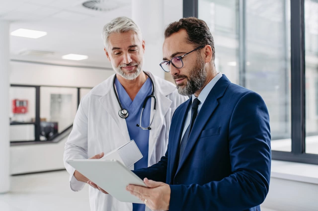 A doctor and a hospital manager reviewing data on a tablet