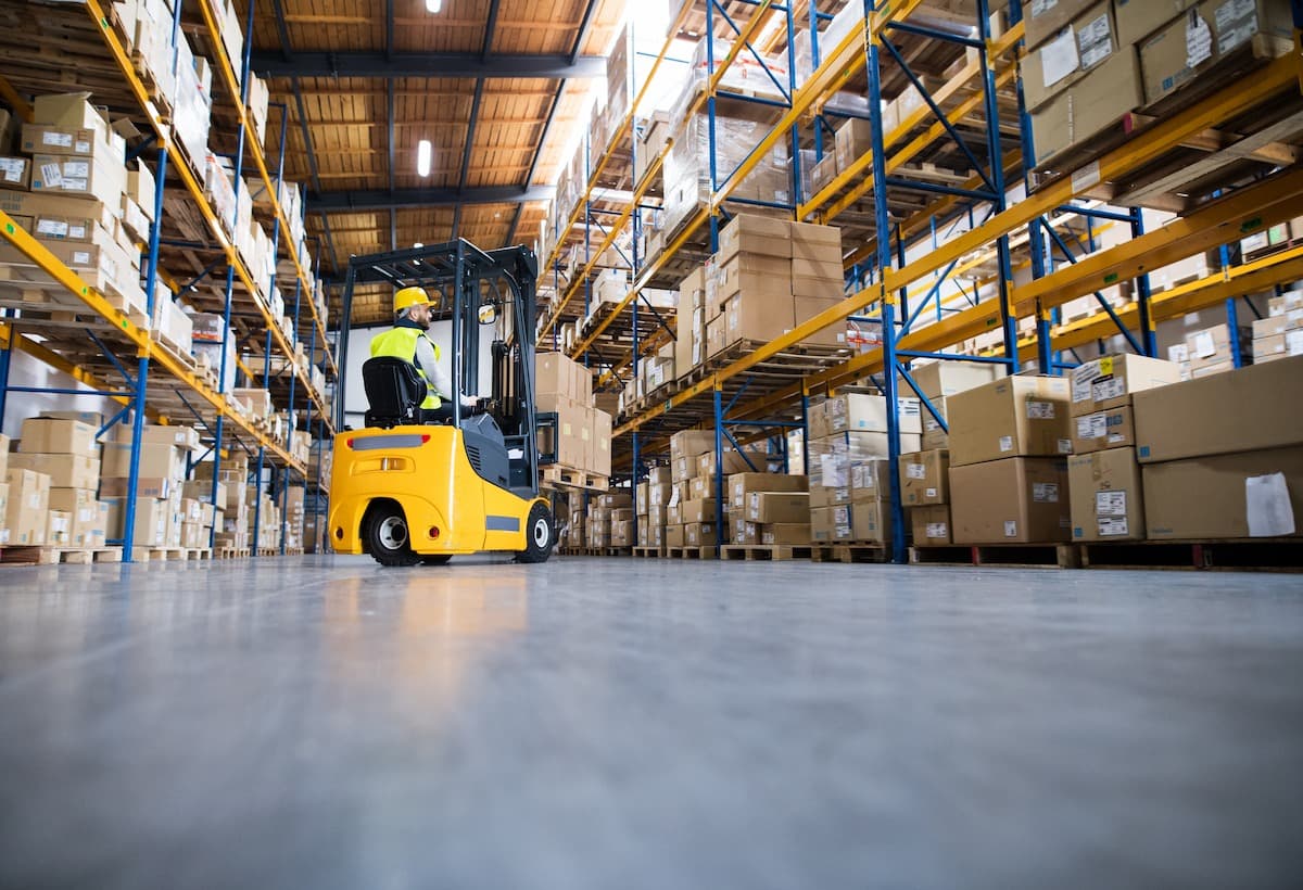 A warehouse forklift operator moving through aisle