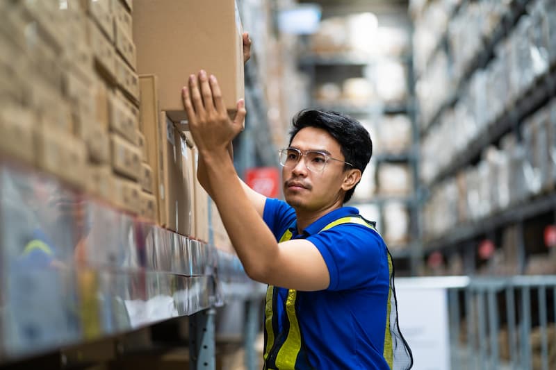 warehouse worker stacking a box on shelves