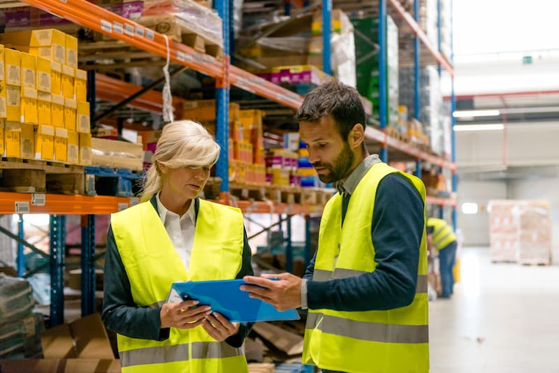 Warehouse colleagues revising inventory documents